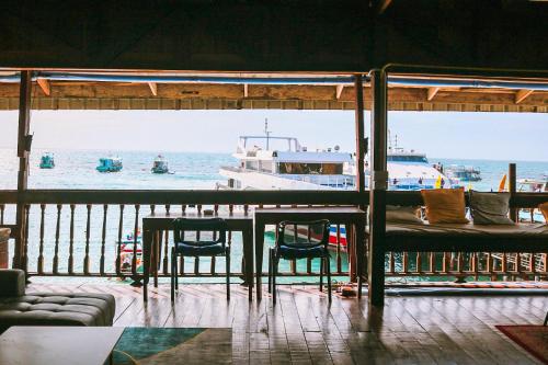 a table and chairs and a boat in the water at WaterMellow Hostel in Koh Tao