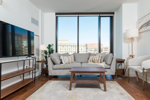 a living room with a couch and large windows at Luxury 2BR BackBay Boston Common T-station Roof Top Lounge Gym in Boston