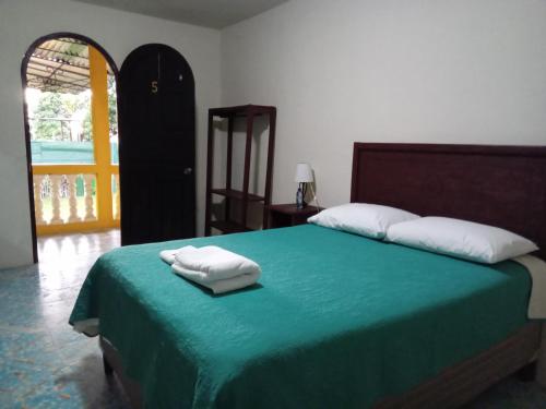 une chambre avec un lit vert avec deux serviettes dessus dans l'établissement Hotel Posada San Jose, à Malacatán