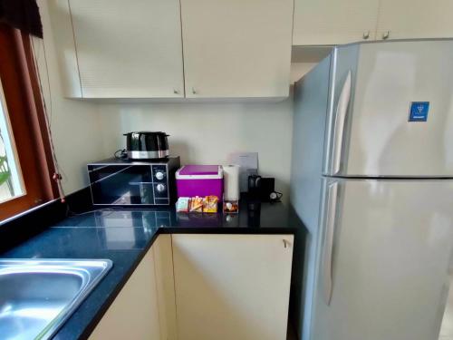a kitchen with a white refrigerator and a sink at Pranaluxe 4 Bedroom Pool Villa C8 in Pran Buri