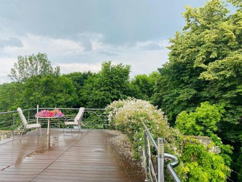 a wooden walkway with chairs and a table and flowers at Rapsodia Pension in Suceava