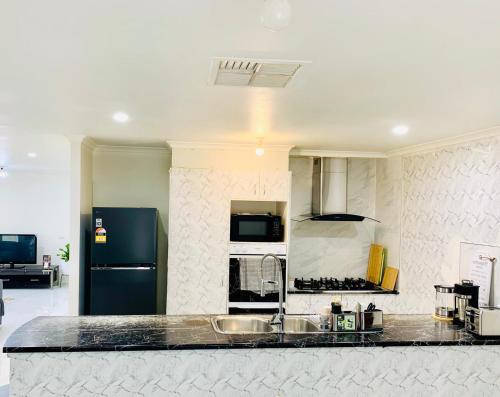 a kitchen with a sink and a black refrigerator at Welcome to Sunny Sanctuary in Carrum Downs