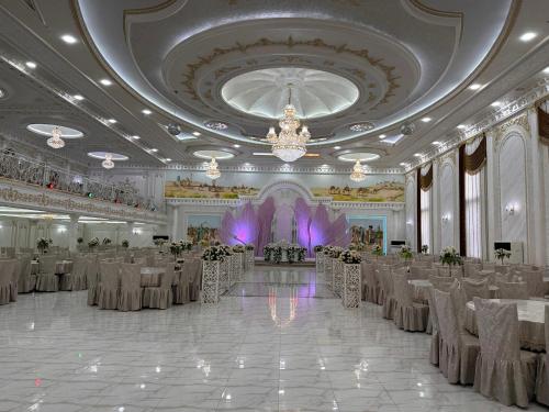a banquet hall with tables and chairs and a chandelier at Qibla Tozabog in Khiva