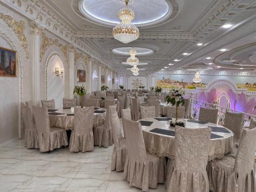 a banquet hall with tables and chairs and a chandelier at Qibla Tozabog in Khiva