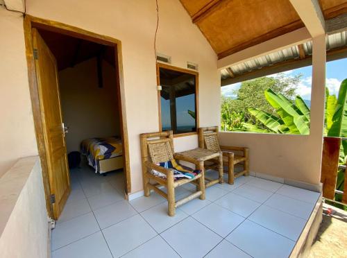 a room with a balcony with two chairs and a bed at Senaru sunset house in Senaru