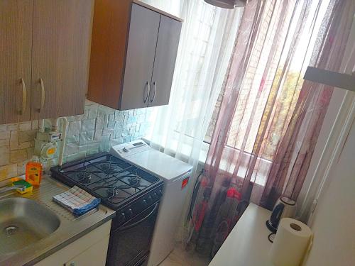 a kitchen with a stove top oven next to a window at Itaja apartment 49 in Šiauliai