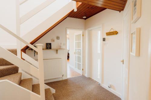 a staircase in a house with white walls and wooden ceilings at Harbour Reach - 2 storey apartment in Saundersfoot in Saundersfoot