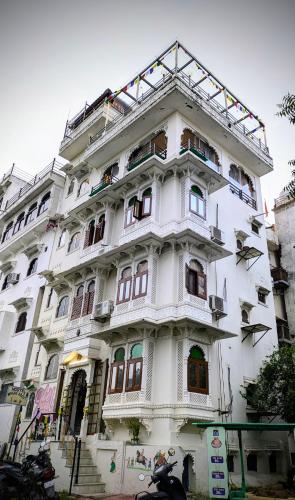 a tall white building with many windows at Whereabout Hostel Udaipur in Udaipur
