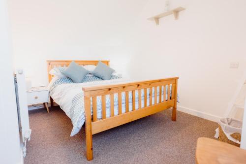a bedroom with a wooden bed with blue pillows at Harbour Reach - 2 storey apartment in Saundersfoot in Saundersfoot