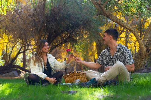 a man and woman sitting in the grass holding a flower at Aldea del Valle - Elqui Villas, Pisco Elqui in Pisco Elqui