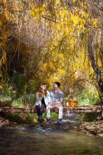 a man and woman sitting on a bench by a stream at Aldea del Valle - Elqui Villas, Pisco Elqui in Pisco Elqui