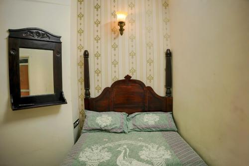 a bedroom with a bed with a wooden headboard and a mirror at Whereabout Hostel Udaipur in Udaipur