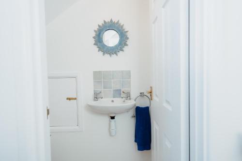a white bathroom with a sink and a mirror at Harbour Reach - 2 storey apartment in Saundersfoot in Saundersfoot