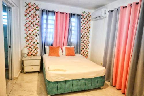 a small bed in a room with colorful curtains at Casa familiar in San Pedro de Macorís