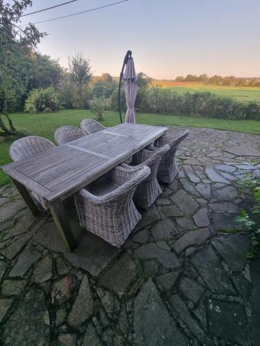 a wooden picnic table and chairs on a stone patio at groot authentiek en charmante woning, 250 vierkante meter, panoramisch vergezicht, zonsondergang, dicht bij Dinant, Maredsous en Namen in Gay