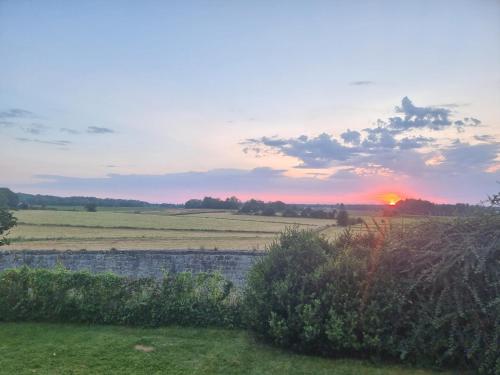 a sunset over a field with a stone wall at groot authentiek en charmante woning, 250 vierkante meter, panoramisch vergezicht, zonsondergang, dicht bij Dinant, Maredsous en Namen in Gay