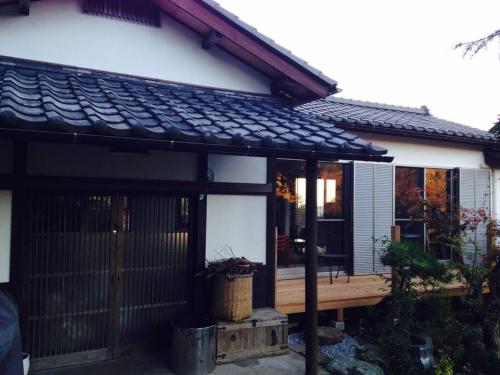 a house with a wooden porch with a roof at 葉山ワンルーム古民家ペット可 bbqグリル&ピザ窯付 in Hayama