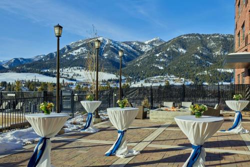 a view of mountains from a patio with white tables at Residence Inn by Marriott Big Sky/The Wilson Hotel in Big Sky