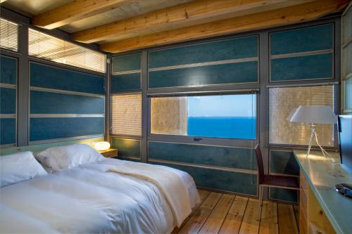 a bedroom with a large bed and a window at Athina Epavlis - Ethereal Charm of Blue Horizons in Ravdhoúkha