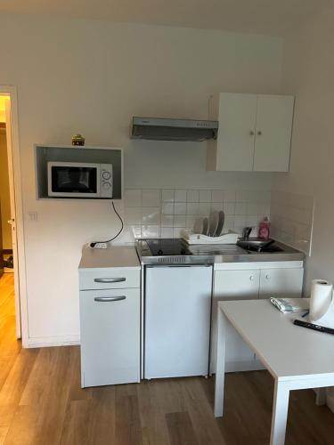 une cuisine avec des armoires blanches et un micro-ondes dans l'établissement Vue Jardin, à Le Chesnay