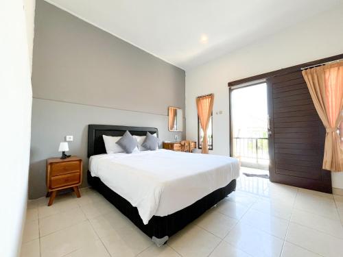 a bedroom with a large bed and a large window at Adi surya guest house in Seminyak