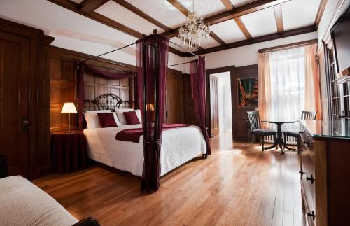 a bedroom with a bed and a table with a chair at Hotel Chateau de l'Argoat in Montréal