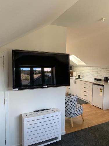 a kitchen with a large flat screen tv on a wall at Parkside Loft in Wanaka