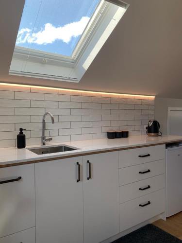 a kitchen with a skylight and white cabinets and a sink at Parkside Loft in Wanaka