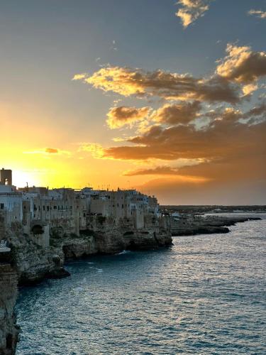 a group of buildings on the water with a sunset at Bella Vista Grotta Ardito in Polignano a Mare