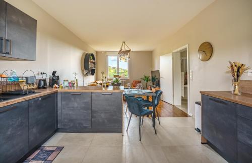 a kitchen with black cabinets and a table with chairs at La Maison du Douanier Apach in Apach