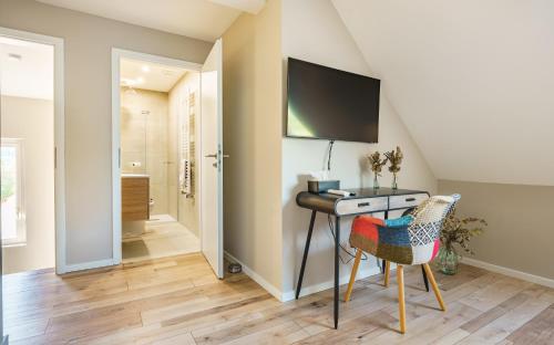 a room with a desk and a television on a wall at La Maison du Douanier Apach in Apach