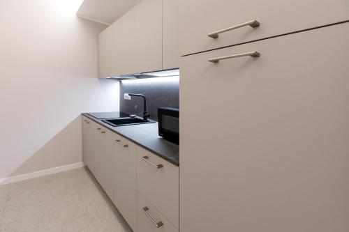 a kitchen with white cabinets and a black counter top at Teatro Romano Exclusive Suites in Trieste