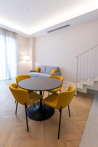 a dining room with a table and yellow chairs at Teatro Romano Exclusive Suites in Trieste