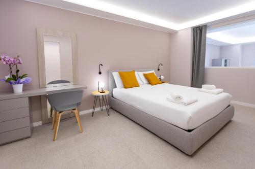 a white bedroom with a bed and a desk and a mirror at Teatro Romano Exclusive Suites in Trieste