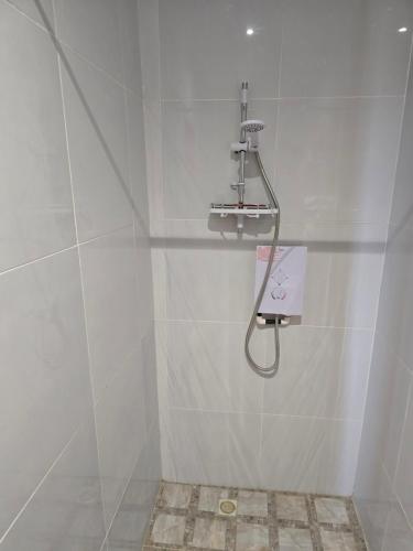 a shower in a white tiled bathroom with a shower head at Cape Coast Travellers' Inn in Cape Coast
