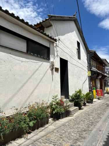 a white building with a door and some plants at Infini House in Dali