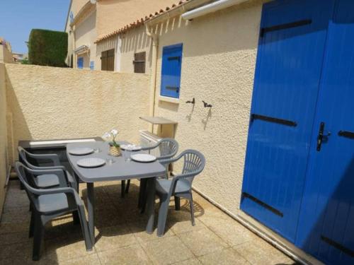 une table et des chaises sur une terrasse avec une porte bleue dans l'établissement L'évasion du Barcarès, à Port-Leucate