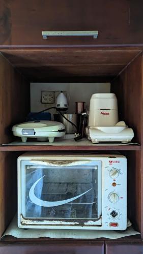 a microwave in a wooden cabinet with aperature at Madu's Mountain View Home in Badureliya
