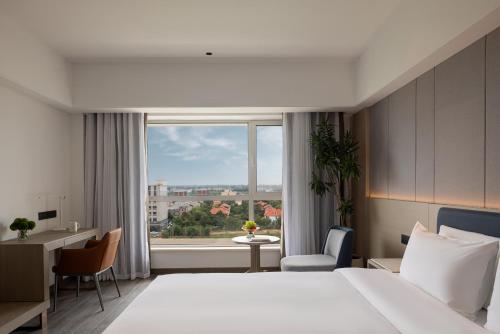 郑州新郑国际机场BlueVisual Hotel Zhengzhou Airport的一间带床和大窗户的酒店房间