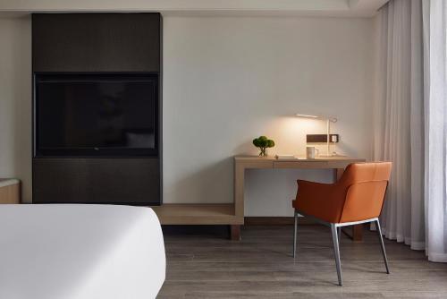 a room with a desk and a television and a chair at BlueVisual Hotel Zhengzhou Airport in Zhengzhou Xinzheng International AIrport