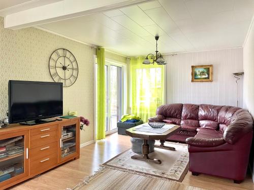 un soggiorno con divano in pelle marrone e TV di Holiday house by riverside with sauna and hottub a Moholm