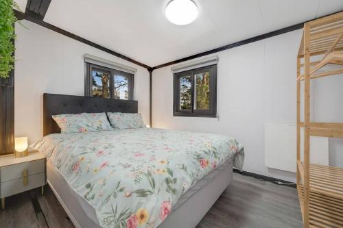 a bedroom with a bed and two windows at 2 bedrooms Cabin 5 min to Pukekohe town centre in Pukekohe East