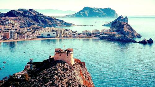 a building on top of a mountain in the water at Incluido clase de Yoga o Pilates in Calabardina