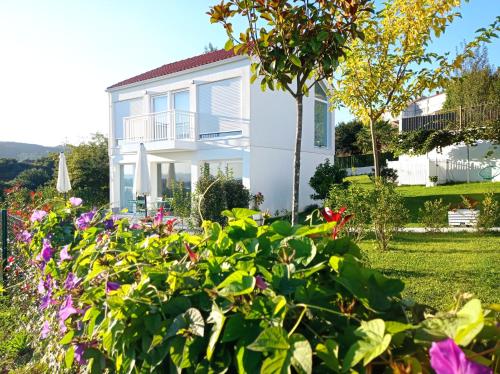 una casa blanca con flores delante en Casas turísticas Lar Jardín - Parking privado, en Santiago de Compostela