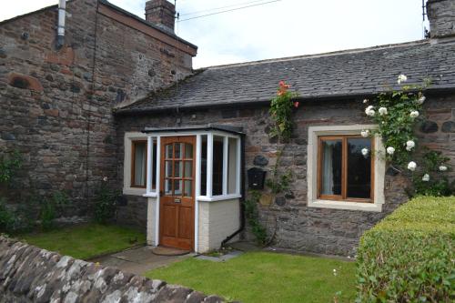 a brick house with a door and a window at Jasmine Cottage, Eamont Bridge in Penrith