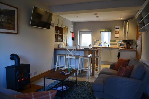 a living room with a couch and a stove at Jasmine Cottage, Eamont Bridge in Penrith