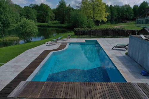 una piscina con panchine accanto a uno specchio d'acqua di Le Relais de Chasse a Clémont
