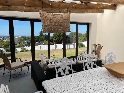 a dining room with a table and chairs and windows at Living Waters in St Francis Bay