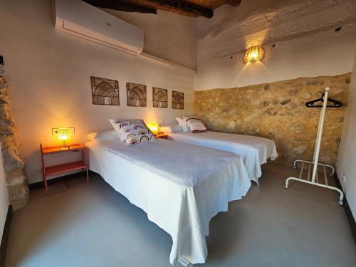 two beds in a room with two lamps and a cross on the wall at Apartamentos Rurales LA BUENA ESTRELLA in Alcalá del Júcar