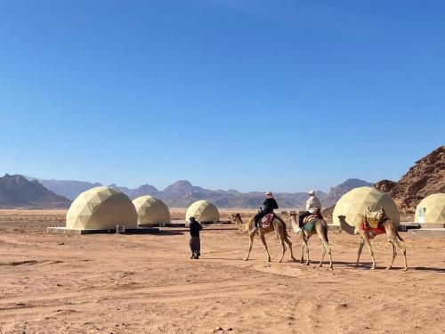 a group of people riding camels in the desert at Wadi Rum The ARC camp in Wadi Rum